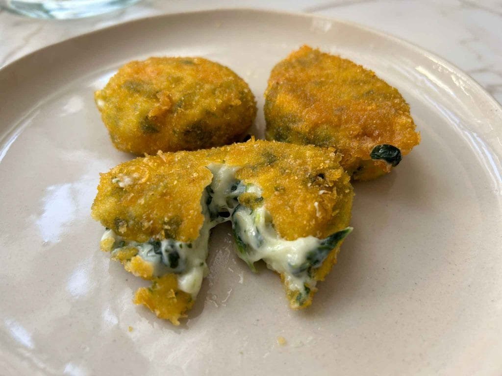croqueta abierta con el interior blanco y con manchas verdes 